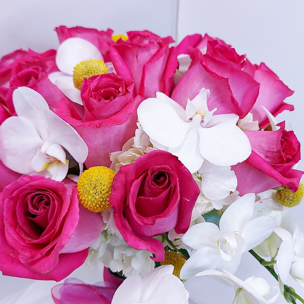 Closeup detail of brightly colored mixed flower bouquet by Heather Floral, featuring white Phalaenopsis orchids and pink roses
